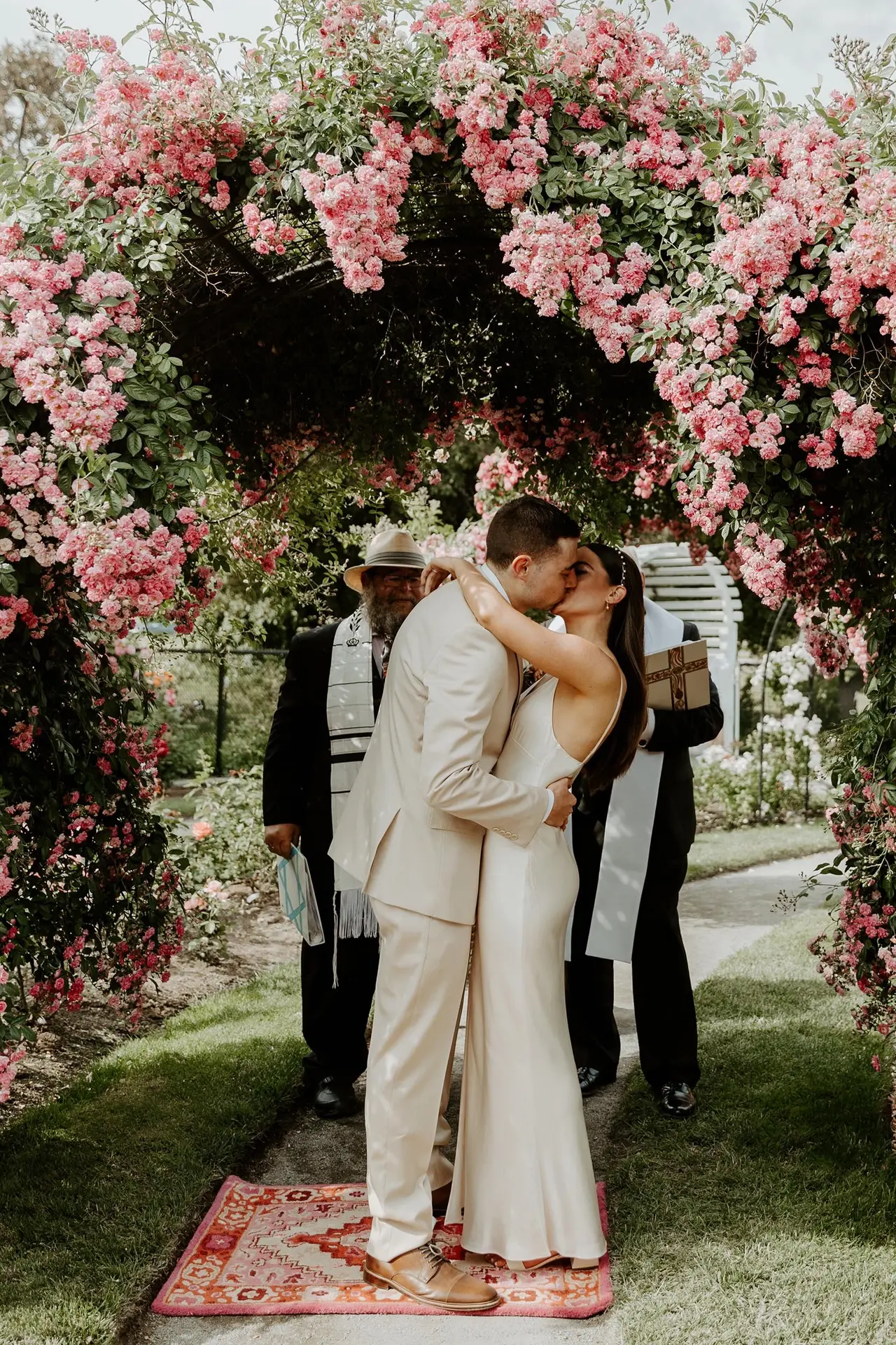 bride and groom kissing under floral arch