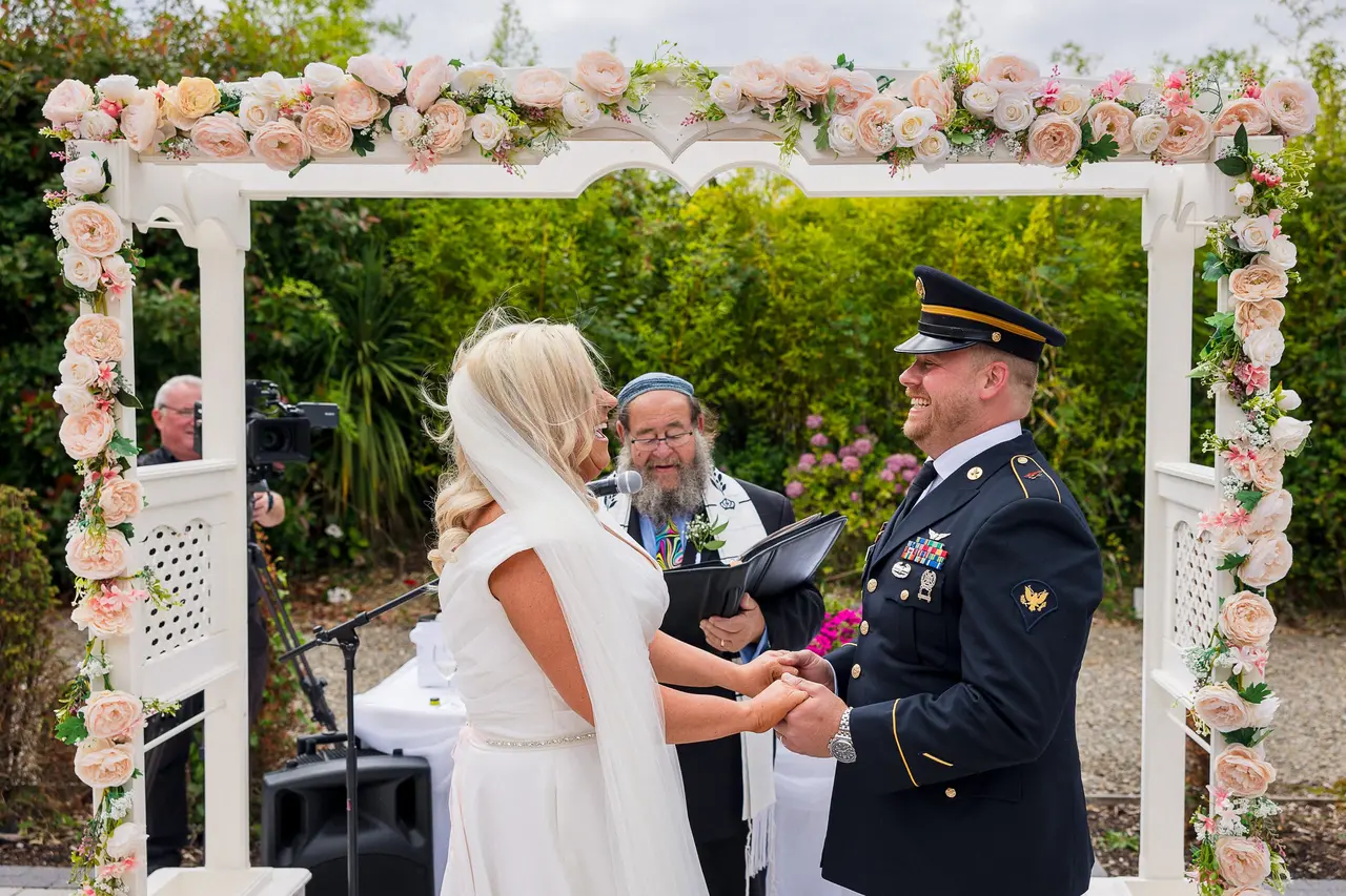 outdoor wedding ceremony under white and floral arch
